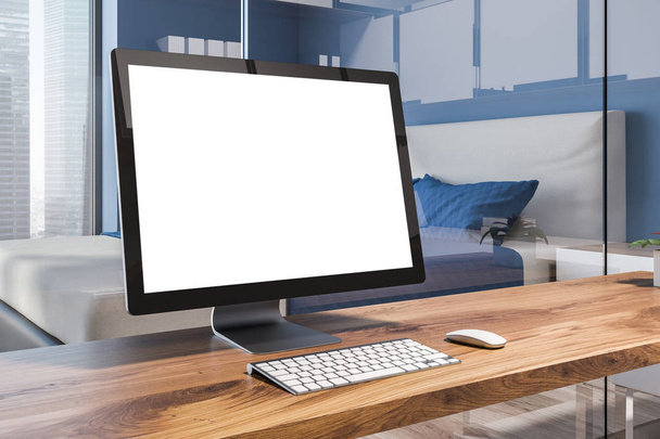Blank computer screen standing on a wooden table in a home office interior situated in a blue wall bedroom. Side view. 3d rendering mock up - Фото, изображение