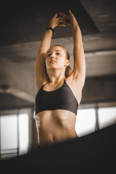 Young long blond woman attractive fitness exercise workout in gym. Woman stretching the muscles and relaxing after exercise on machine treadmill at fitness gym club. - Foto, Imagem