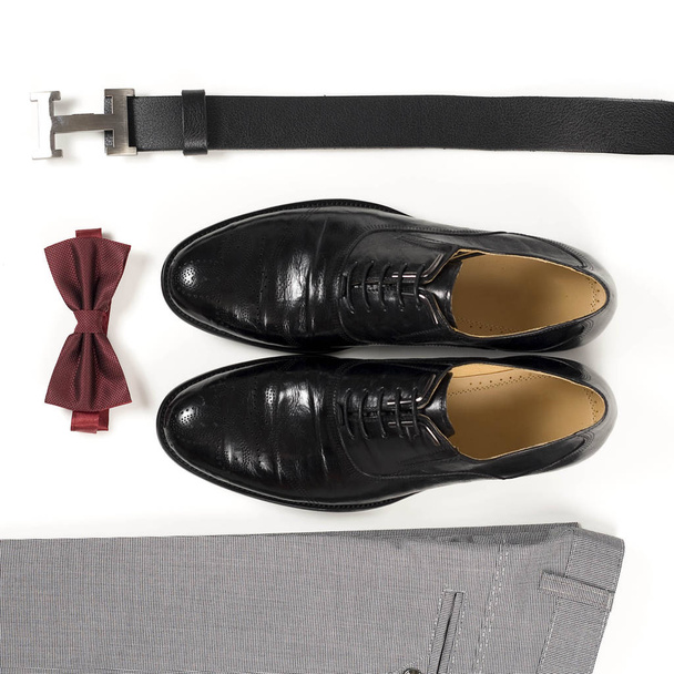 Close up of modern man accessories. Bordeaux bow tie, leather shoes, belt on white  background. Set for formal style of wearing isolated on white background - 写真・画像