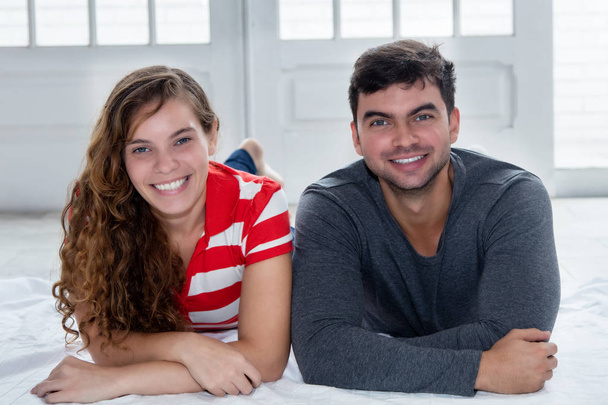 Beautiful caucasian love couple looking at camera indoors in new apartment - Photo, image