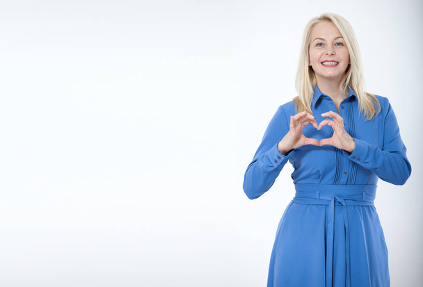 Friendly smiling middle aged woman in blue dress isolated - Foto, imagen