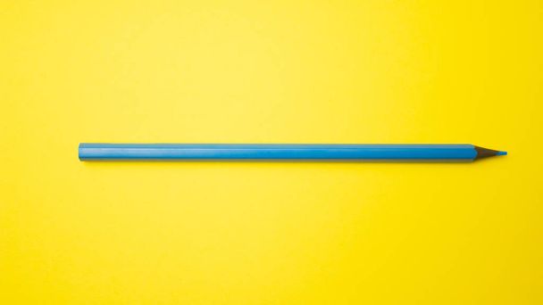 Blue pencil on yellow background. View from above with copy space - Fotó, kép