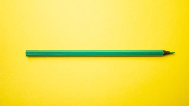 Zielony ołówek na żółtym tle. Widok z góry miejsce - Zdjęcie, obraz