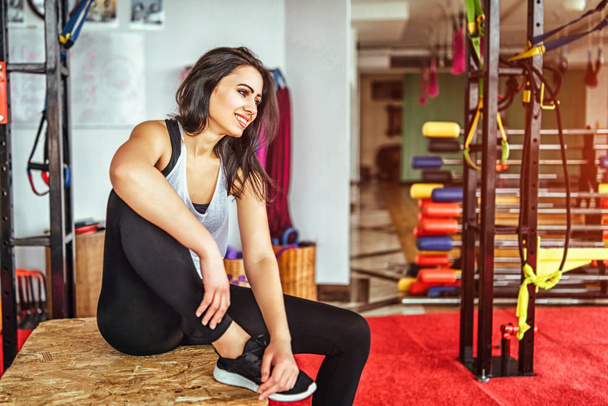 Pretty sporty girl sitting in gym after workout - Фото, изображение