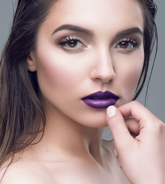 Studio portret van mooie jonge vrouw met paarse lippen en NAT bruin haar - Foto, afbeelding