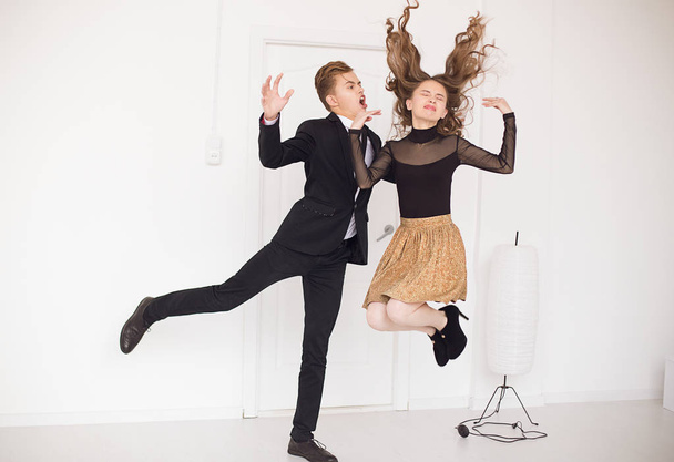 screaming guy and jumping girl with closed eyes and windy long hair up in white room. - Foto, imagen