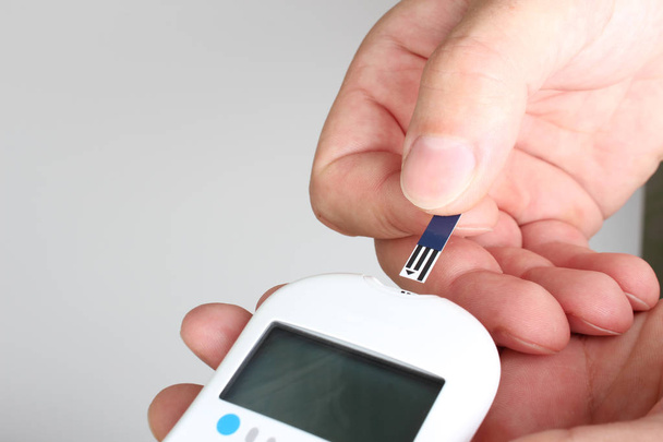 blood glucose meter hand light background - Фото, изображение