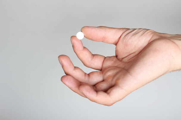 pilules blanches dans une main sur un fond clair
 - Photo, image