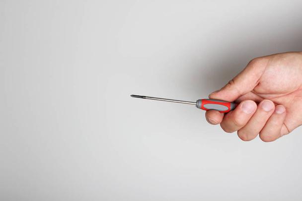 screwdriver repair in hand on a light background - Foto, Bild