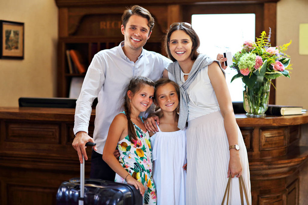 Ευτυχισμένη οικογένεια τον έλεγχο στο ξενοδοχείο στη ρεσεψιόν - Φωτογραφία, εικόνα