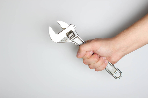 wrench in hand on a light background - Foto, Bild