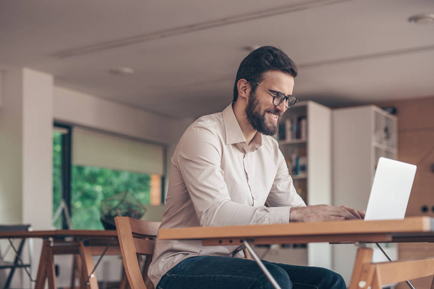 Usmívající se podnikatel s notebookem v coworkingu - Fotografie, Obrázek