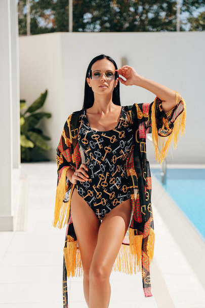 fashion outdoor photo of beautiful sexy woman with dark hair in elegant swimming suit relaxing in luxurious villa - Photo, image