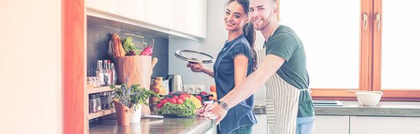 Couple cooking together in their kitchen at home - 写真・画像