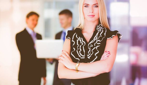 Business woman standing in foreground  in office - Fotoğraf, Görsel