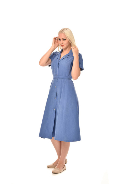 full length portrait of blonde girl wearing blue dress. standing pose. isolated on white  studio background. - Foto, imagen