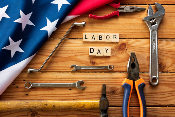 USA Concept de fête du travail, premier lundi de septembre. Différents types de clés, outils pratiques, drapeau américain et blocs de bois sur table en bois
. - Photo, image
