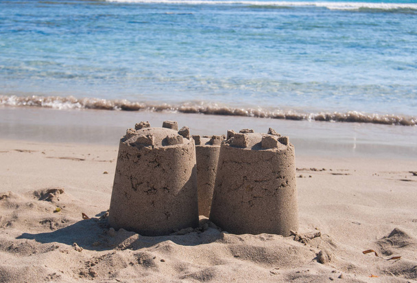 Kasteel van zand met drie torens door de zee - Foto, afbeelding