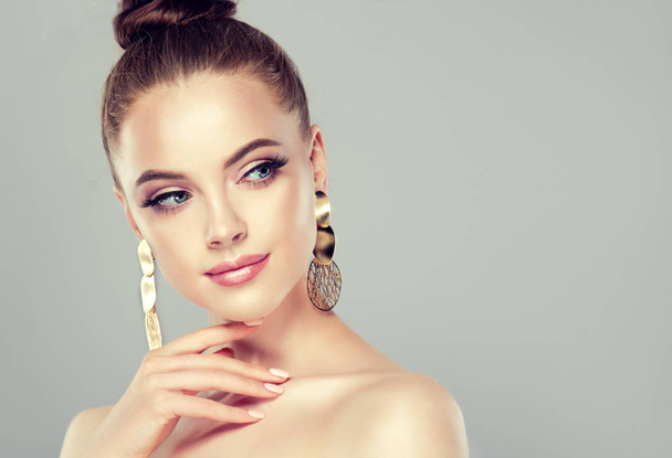 Beautiful model girl with  manicure on nails . Fashion makeup and cosmetics . Big golden shine earrings jewelry . - 写真・画像