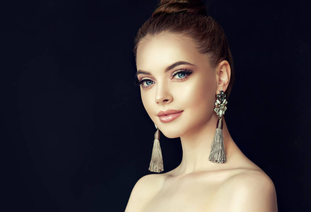 Beautiful model girl with  Fashion makeup and cosmetics . Big golden shine earrings jewelry . - Photo, Image