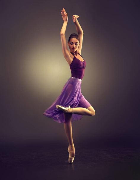Ballerina. Young graceful woman ballet dancer, dressed in professional outfit, shoes and  weightless skirt is demonstrating dancing skill. Beauty of classic ballet. - Photo, Image