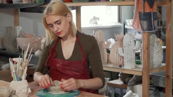 Чудова молода жінка посміхається під час роботи з глиною на майстерні
 - Кадри, відео