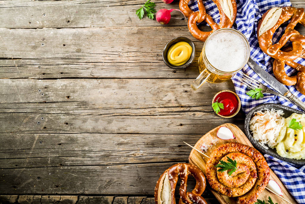Oktoberfest menu żywności, bawarskie kiełbaski z precle, tłuczone ziemniaki, kapusta kiszona, piwo butelka i kubek stare rustykalne drewniane tła, kopia miejsce wyzej - Zdjęcie, obraz