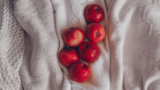 Composição do outono. Maçãs vermelhas em camisolas brancas de malha. Cena caseira aconchegante quieta. colheita, colheita, colheita. Conceito outono
 - Foto, Imagem