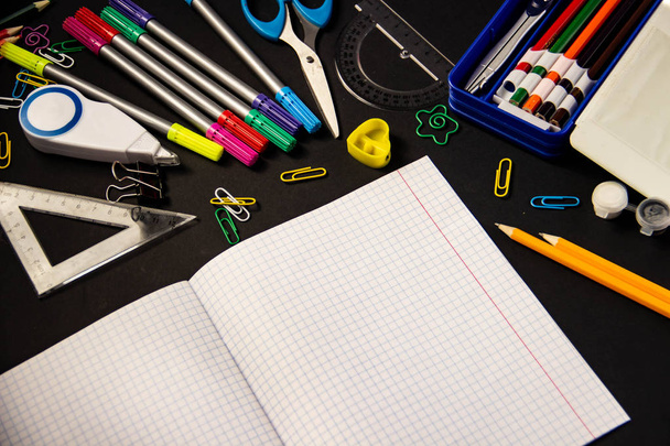 Produkt, długopisy, ołówki, spinacze, kredki, linijki, kleju, korektor, znacznik, nożyczki, notebook ostrzenia na czarnym tle z miejsca pod tekstem - Zdjęcie, obraz