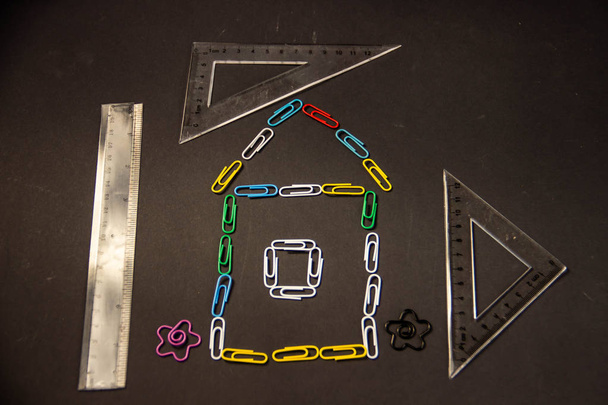 Casa feita de clipes de papel coloridos em um fundo preto
 - Foto, Imagem