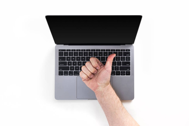 Vista superior da mesa com laptop e mão mostrando polegares para cima sinal isolado no fundo branco
 - Foto, Imagem
