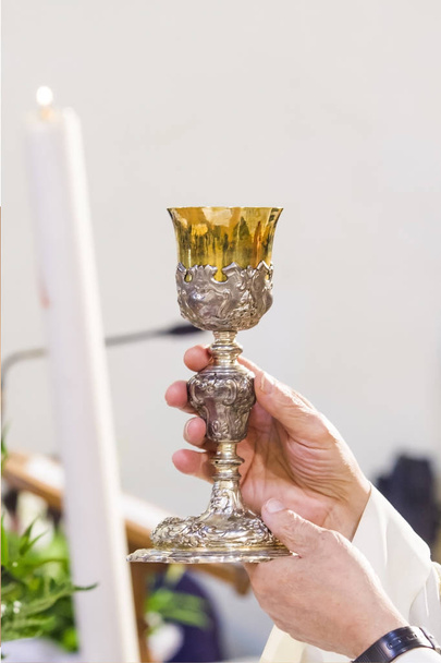 Heiliger Wein wird zum Blut Christi, dem Retter der Sünden der Menschen in den Händen des Priesters während der Messe - Foto, Bild