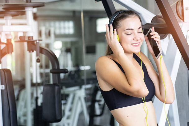 Woman Listening Music, Doing Workout Exercises.Relaxing After Fitness Training in gym.She smile and happy. - Фото, зображення