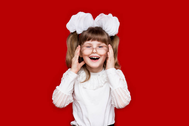 Porträt eines fröhlichen kleinen Mädchens mit sehr großer Brille, isoliert auf Rot. Konzept des Sehens oder des Unterrichts. Bildungs- und Wissenskonzept - Foto, Bild