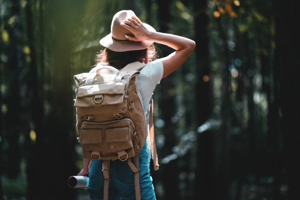 Samotna kobieta podróży wśród lasu z plecaka. Młody podróżnik w ręku na sobie kapelusz i przytrzymaj mapy kierunkowej - Zdjęcie, obraz