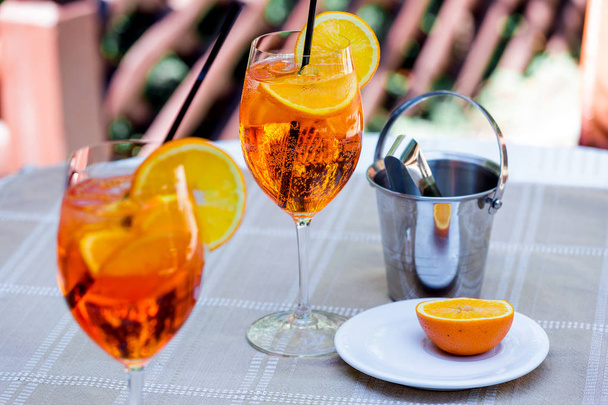 Aperol spritz cocktail em vidro na mesa de madeira. Dois copos com um coquetel e um balde de gelo na mesa
. - Foto, Imagem