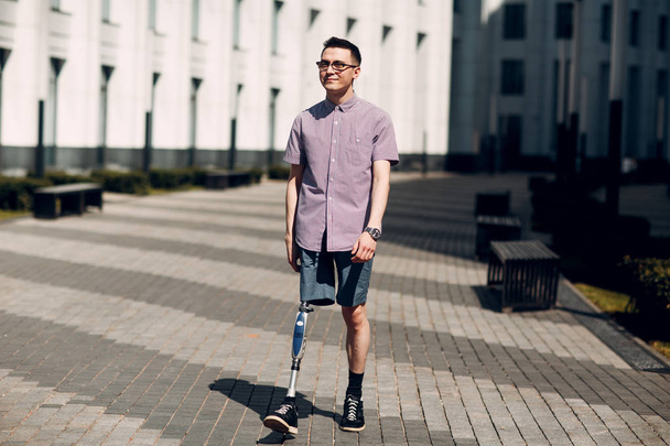 Fogyatékkal élő fiatalember protézis láb sétál az utcán. - Fotó, kép