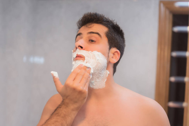 Hombre guapo afeitándose la barba en el baño
 - Foto, imagen