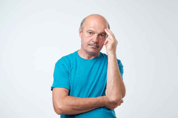 Closeup portrait of sleepy mature man in blue t-shirt, funny guy placing head on hand, unhappy looking at camera. I am too old for all this deals concept - Foto, imagen