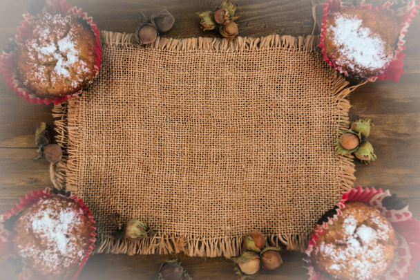 Galletas de avena en formas de papel rojo sobre un fondo de madera con nueces y una servilleta de tela, diseño de recetas de postre
. - Foto, imagen