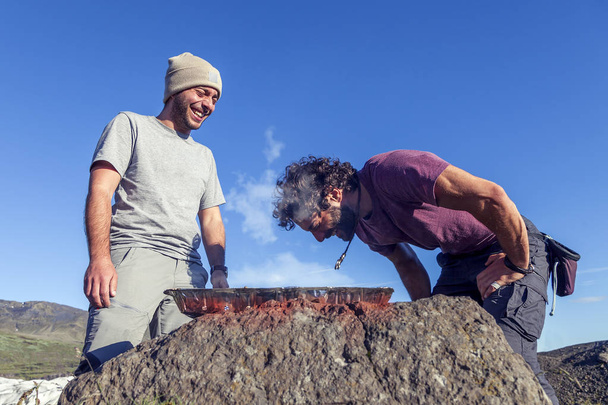 couple of friends preparing a barbecue outdoors in the desolate land of iceland - Foto, Imagem