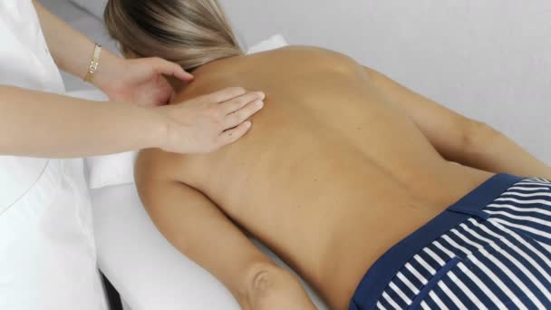 Мануальний терапевт масажує молоду жінку, що лежить на масажному столі, натискаючи на спину
 - Кадри, відео