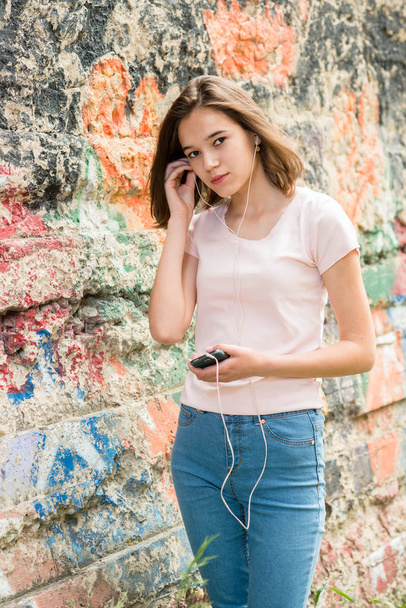 jeune fille brune en t-shirt blanc et jeans écoutant de la musique avec écouteurs
 - Photo, image