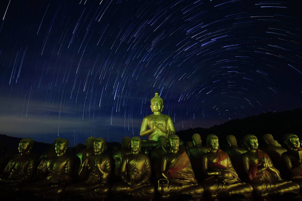 仏と彼の弟子たちは、星のふたの夜空の下で瞑想します。仏教信仰と宗教の信念のゴールド色の彫刻。Nakornayok バンコクの北東地域のタイ芸術スタイル. - 写真・画像