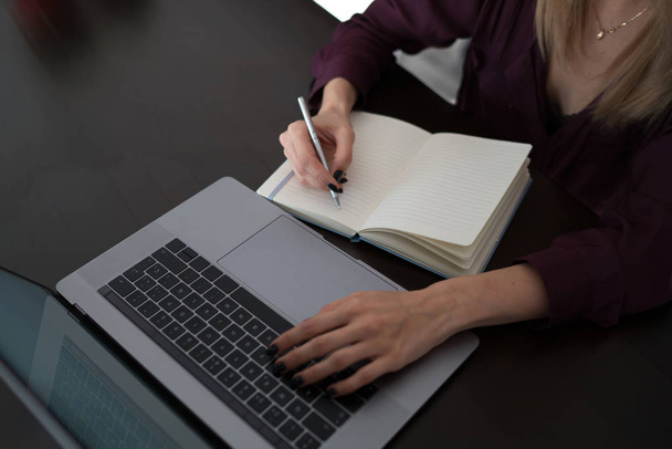 Female designer using laptop, sketching at blank notepad. Woman hand writing in notebook on wooden desk. Concept ease of use of Internet and accessibility of information of working process. - Foto, Bild