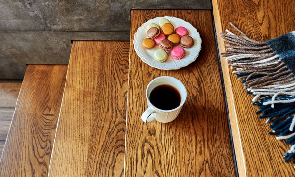 Colorful macaroons cookies on rustic wooden background with hot tea mug. - Foto, imagen