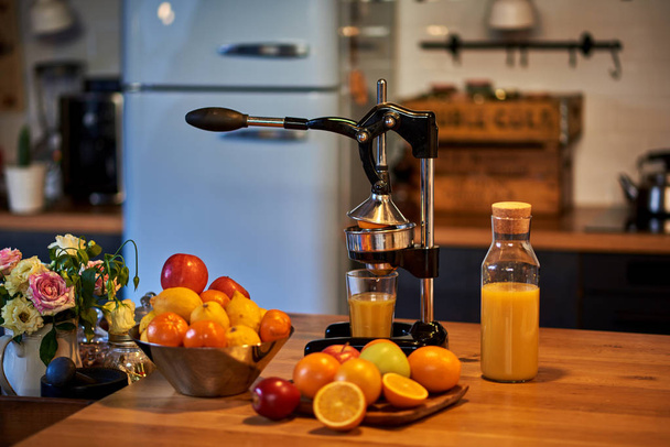 Imprensa de citrinos com laranjas e suco em vidro no fundo da cozinha rústica velha
. - Foto, Imagem
