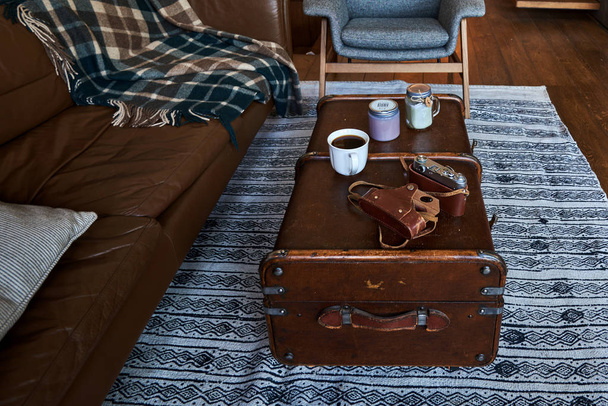 Resting place with sofa and plaid. Retro camera and cup coffee on wooden table.   - Фото, зображення