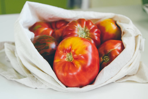 Canvas eco tote with red tomatoes. Local market vegetables. Eco friendly grocery bag - Photo, Image