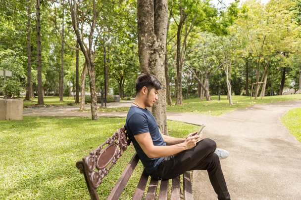 Молодий Ділова людина використовувати планшет і сидіти на стільці в парку. - Фото, зображення